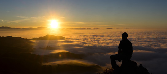 Fototapeta na wymiar Silhouette of man on top of mountain at sunset. Conceptual scene.