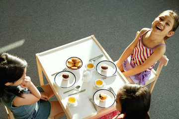 Three girls at tea party, one girl smiling at camera