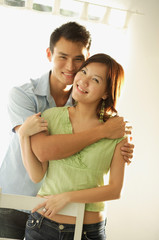 Couple standing together, embracing, smiling at camera