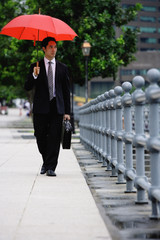 Businessman walking under red umbrella
