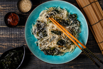 Funchoza salad with wakame on dark background.