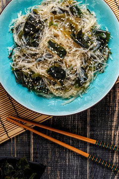 Funchoza salad with wakame on dark background.