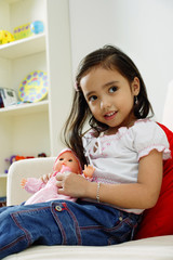Young girl playing with doll, smiling