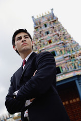 Businessman standing with arms crossed, Hindu temple in the background