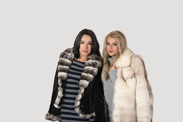 two  girlfriends in short fur coats walk