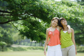 Two young women, arms around each other, smiling at camera