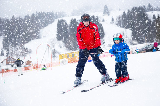 Happy little boy learning skiing with his father in Swiss Alps
