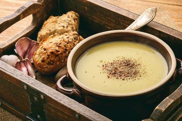 Garlic cream soup with cheese on brown wooden background.