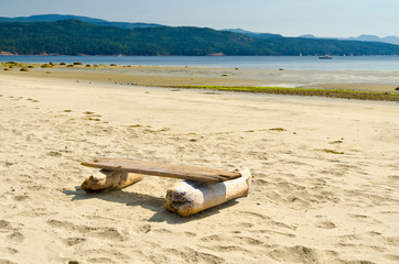 Fototapeta na wymiar Picnic bench (log) on the beach of the ocean in Canada.