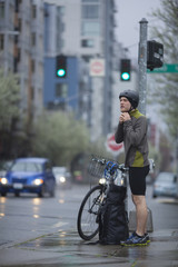 An adult man, stopped on a Seattle, Washington street corner, preparing for a rainy morning bike commute.