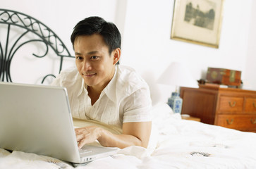 Man in bedroom, using laptop