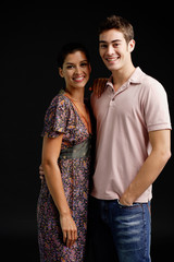 Couple in studio, standing side by side, smiling at camera