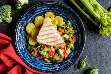 Grilled tuna steaks with steamed broccoli, red pepper, zucchini, parsley, stalk celery and carrot