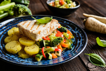 Grilled tuna steaks with steamed broccoli, red pepper, zucchini, parsley, stalk celery and carrot