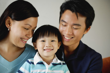 Young boy between mother and father, smiling at camera