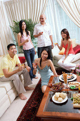 Adults in living room, smiling at camera, social gathering