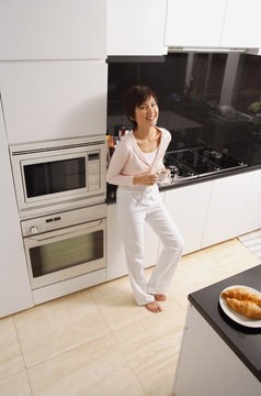 Young woman standing in kitchen, looking at camera, smiling