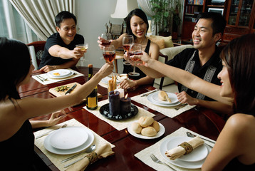 Adults toasting with wine glasses across dining table