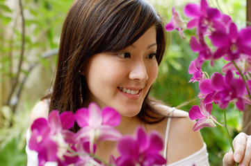Naklejka premium Young woman looking at orchids