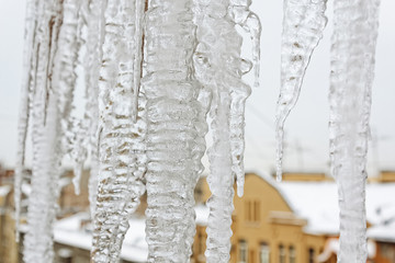Bright icicles which are hanging down from a roof. Ice texture.