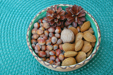 walnuts, hazelnuts and almonds in shells, one upon the other in ceramic bowl