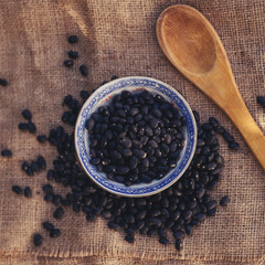 Black beans in the plate with wooden spoon