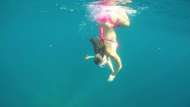 SLOW MOTION UNDERWATER: Young woman in bikini snorkeling in crystal clear ocean
