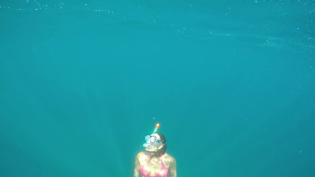SLOW MOTION UNDERWATER: Girl snorkeling in sea, swimming to the surface for air