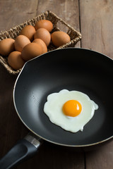 Fried egg on pan and fresh eggs.