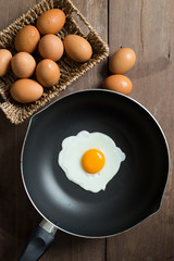 Fried egg on pan and fresh eggs.