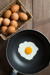 Fried egg on pan and fresh eggs.
