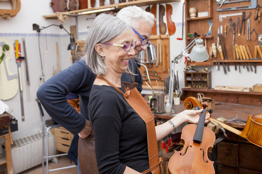 group of mature violin maker in pose while testing the violins i