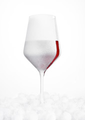 Glass of red wine covered with snow and frost