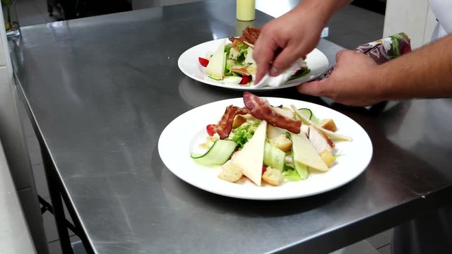 Caesar salad is on professional kitchen Chef pours sauce dish before serving customers of the restaurant, a salad with vegetables and meat cooked in a restaurant, a caf for guests