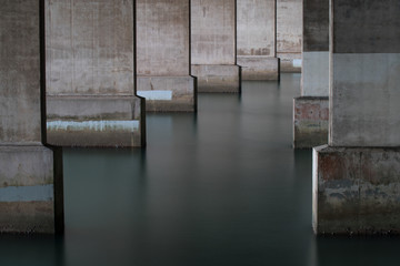 Support pillars for Auckland Harbor Bridge with glossy water and concrete frame