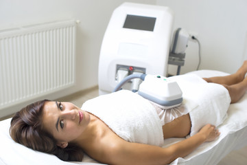 Pretty young woman getting cryolipolyse treatment in cosmetic ca