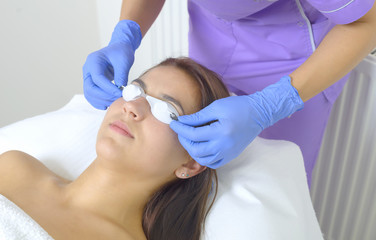Woman lying on a table with protect glasses on eyes getting a laser skin treatment