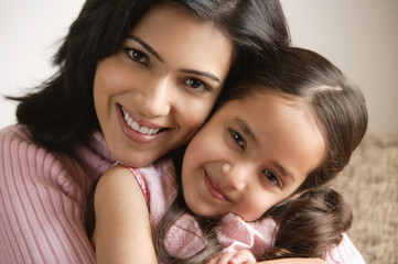 close up of mother and daughter hugging and smiling at camera