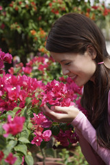 Fototapeta premium Young woman holding up flowers to smell
