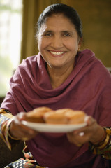 older woman offering food, smiling at camera