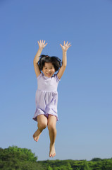 Girl jumping in mid air, arms outstretched, smiling
