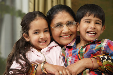 grandmother hugs grandkids, all smile at camera