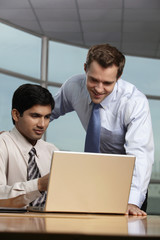 Caucasian man looking at laptop with Indian man