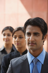 one businessman in foreground, two businesswomen in background (vertical)