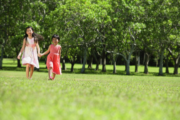 Obraz premium Girls holding hands, walking across park