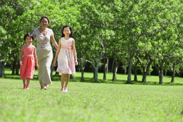 Fototapeta premium Mother and two daughters walking across field