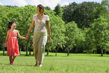 Mother and daughter, holding hands, walking in park