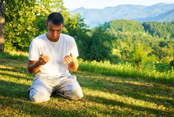 Young Muslim man pray in nature at sunset time - obrazy, fototapety, plakaty