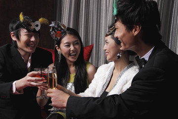 Two couples celebrating at a party, toasting each other