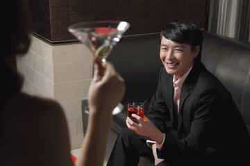 Young woman looking at young man holding a drink and smiling